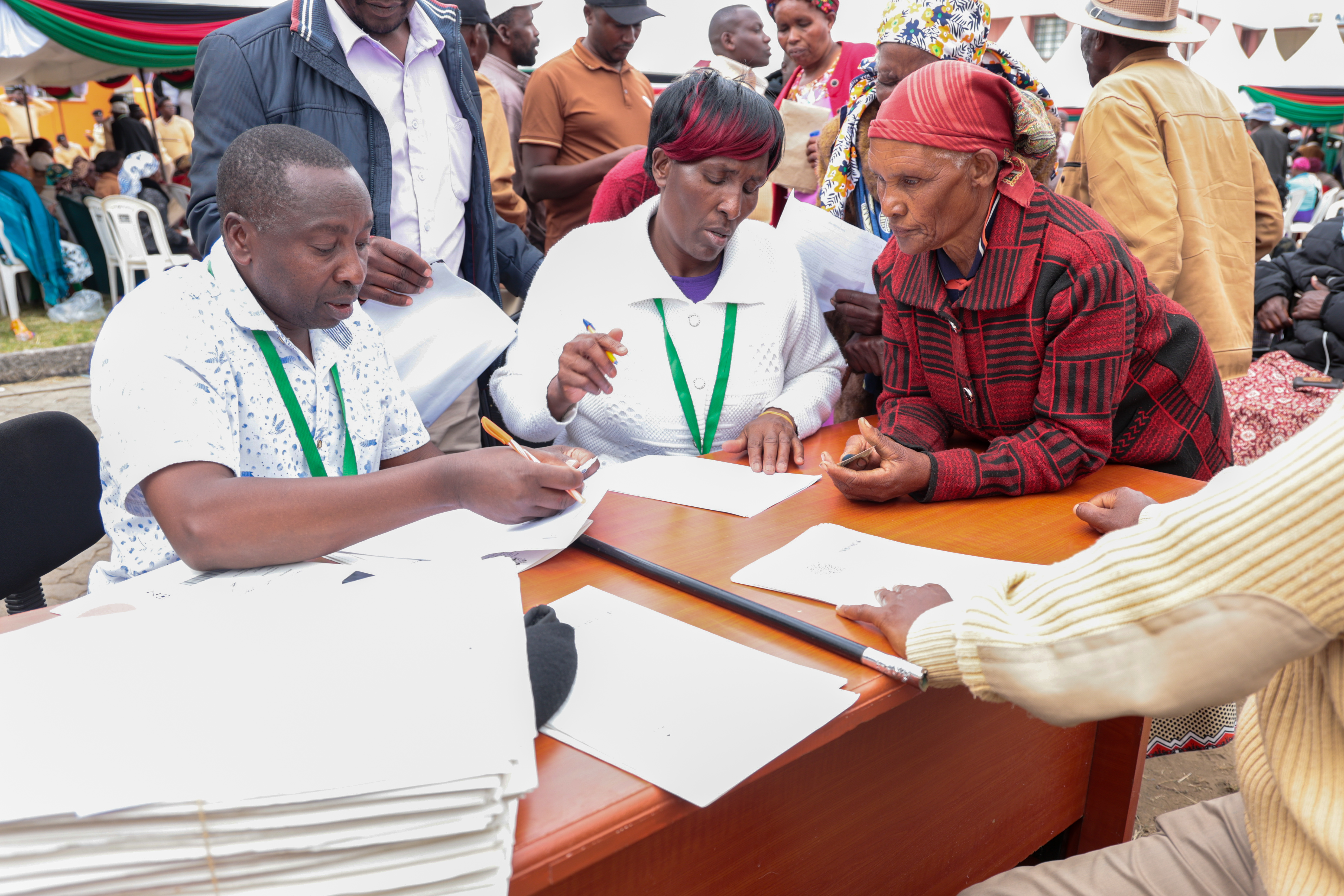 Registrars assist an elderly beneficiary with title registration process during the issuance of title deeds for the  Colonial Villages in Nyandarua county